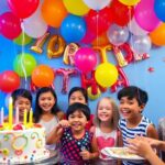 Scène de fête d'anniversaire avec des ballons et un gâteau.