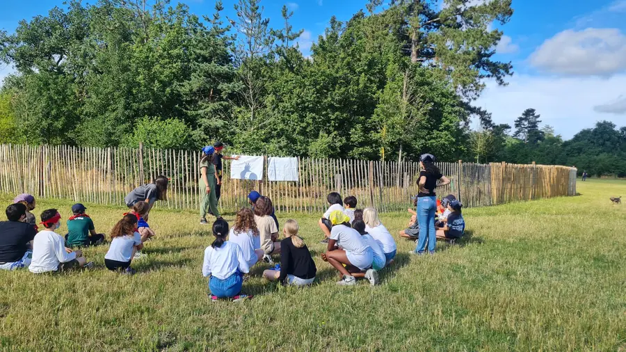 Des enfants écoutent leur animateur dans un parc