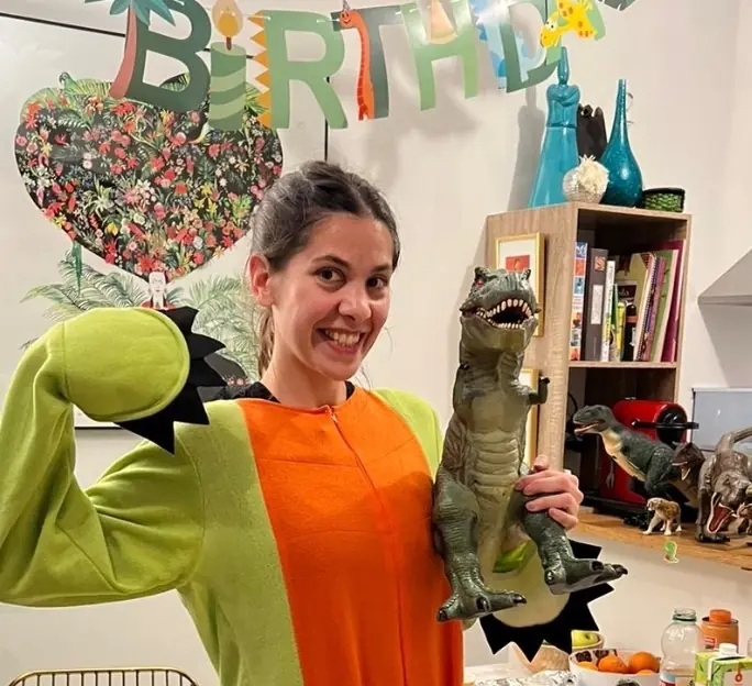Une animatrice Kidays en costume de dinosaure tient un T-Rex en jouet