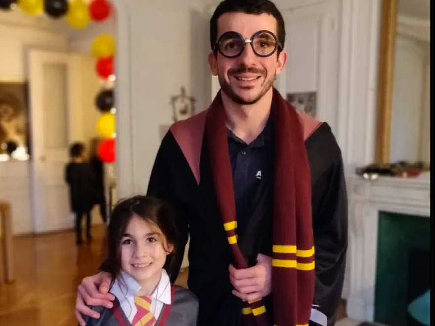 Un animateur Kidays en tenue de sorcier pose avec une petite sorcière
