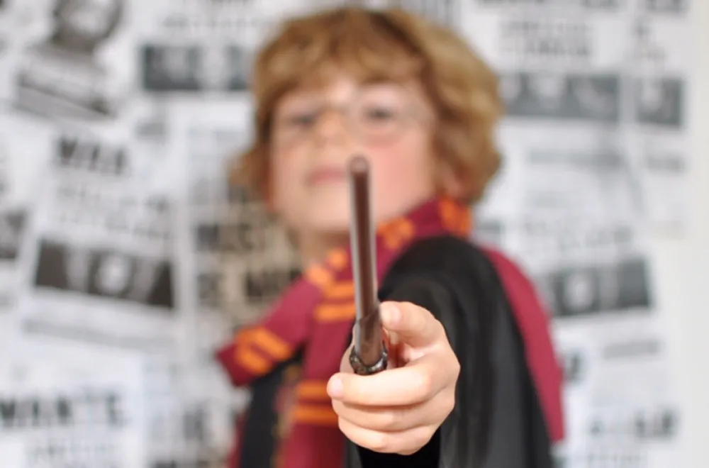 Un enfant en robe de sorcier tend sa baguette magique