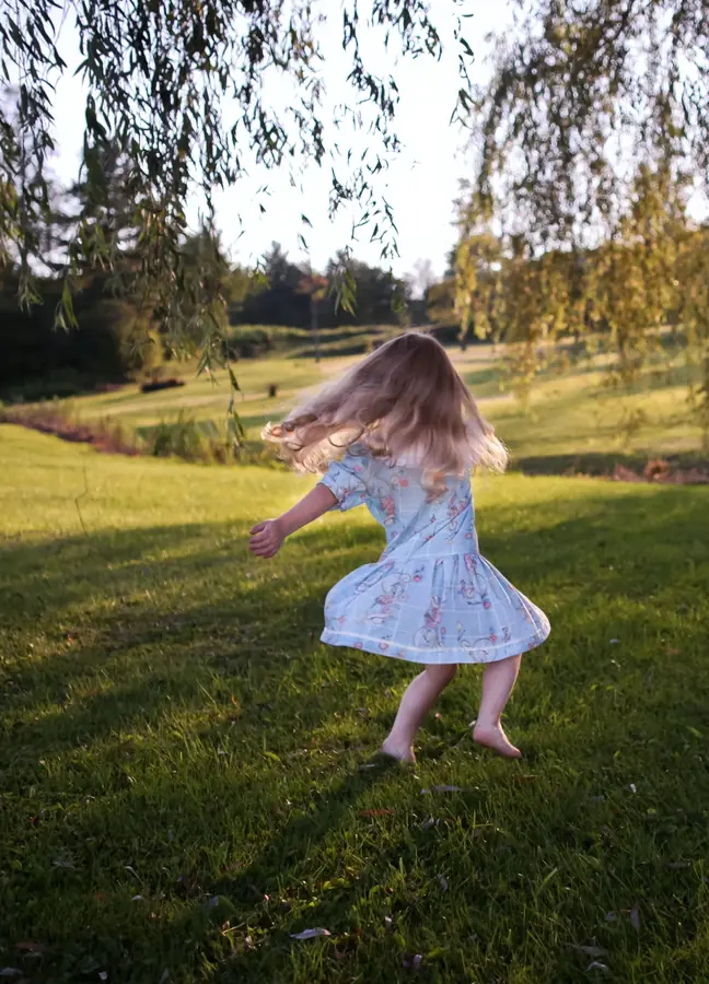 Une petite fille virevolte dans un jardin