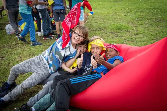 Des enfants en bandana rient sur un pouf gonflable