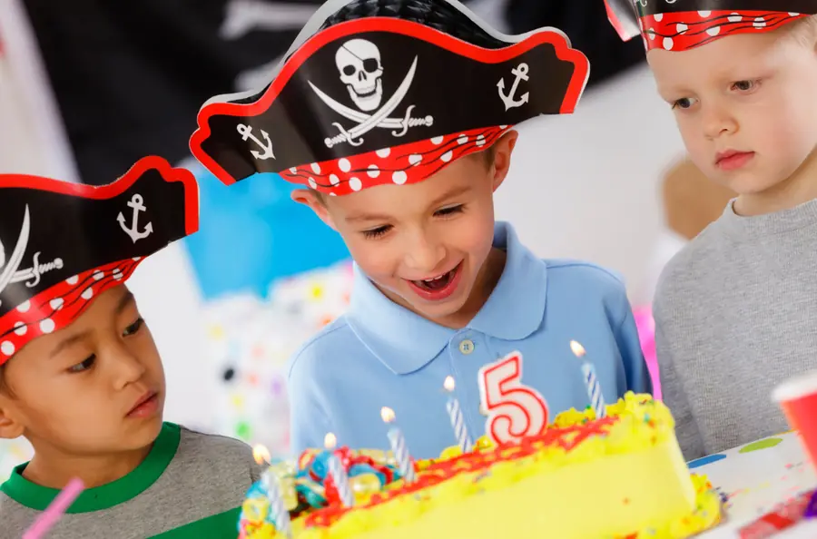 Des enfants en chapeau de pirate devant un gâteau d’anniversaire