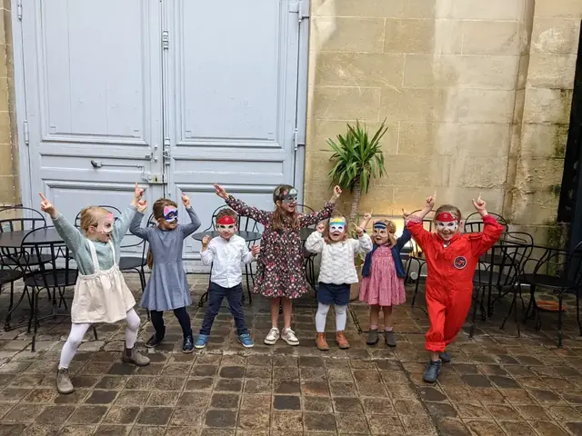 Des enfants masqués lèvent les bras avec leur animateur