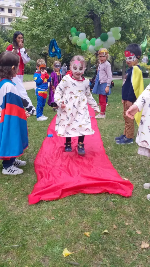 Des enfants costumés défilent sur un tapis rouge dans un parc